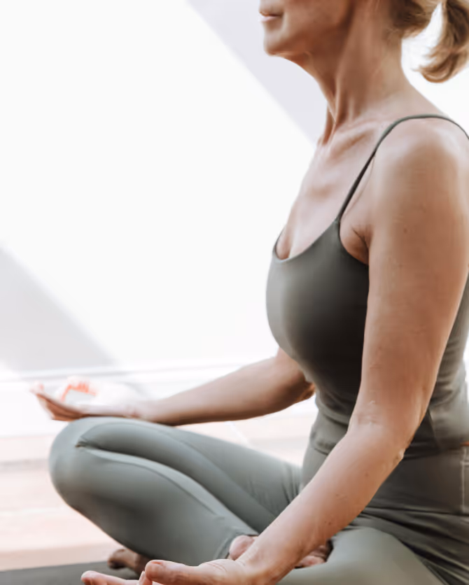 Woman sitting cross-legged in meditation, hands resting on her knees.